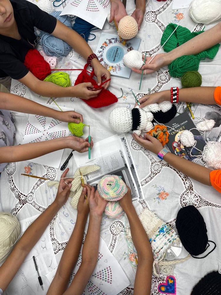 Children crocheting together at the studio worktable